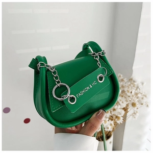 Détail d'un sac selle vert en similicuir avec chaîne en métal argenté et accessoire de mode