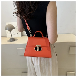 Dettaglio di borsa a tracolla rosso-arancio in pelle con chiusura girevole dorata
