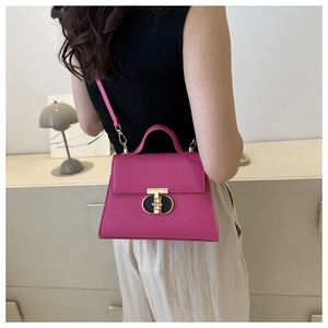 Dettaglio borsa a trapezio rosso rosa con chiusura a T dorata e trama in pelle