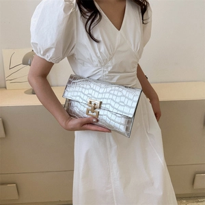 Silver crocodile embossed envelope clutch bag with gold ring buckle shown by model