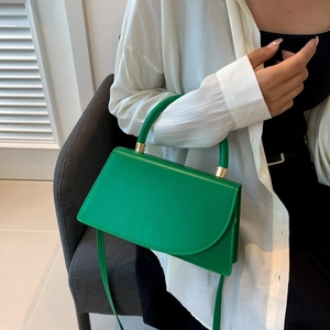 Minimalist bright green leather satchel handbag with golden hardware shown with model