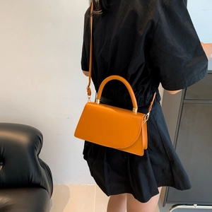 Ginger yellow leather handbag for women featuring a top handle and shoulder strap