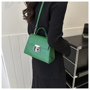 Dettaglio borsa in pelle verde con chiusura ovale in metallo e tracolla regolabile