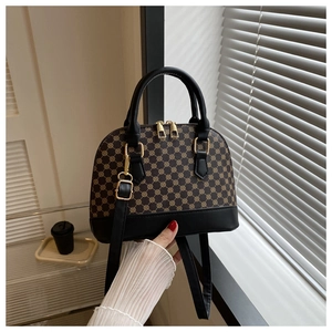 Detailed close-up of shell-shaped handbag with dark brown monogram and gold hardware