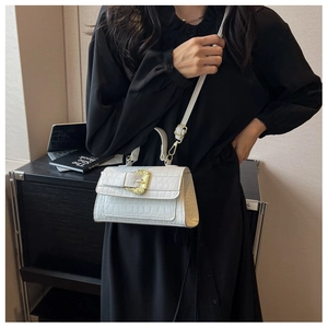 Detail of white crocodile embossed small square bag with golden buckle and adjustable strap