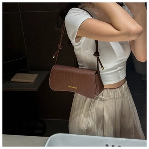 Close-up of brown crocodile texture shoulder bag with gold hardware and knot strap