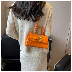 Detailed back view of a bright orange crocodile pattern handbag with gold baroque buckle