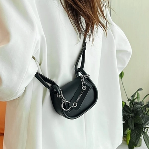 Mini sac selle noir chic avec chaîne argentée et étiquette sur blazer blanc