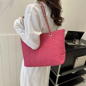Pink quilted tote bag with chain strap shown on a model in a modern office setting