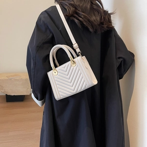 Chic quilted beige leather handbag with woven handle and gold hardware shown on a model