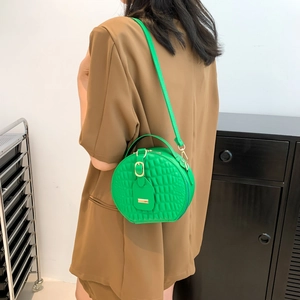 Bright green quilted round crossbody bag with gold hardware shown on a female model
