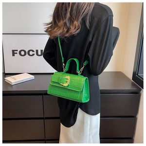 Detail of green croc-embossed handbag featuring a gold Baroque-style metal buckle
