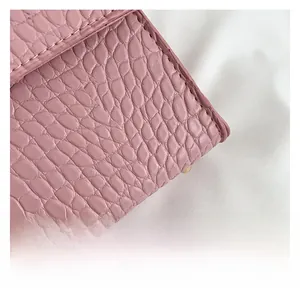 Detail of pink crocodile pattern leather bag showing fine stitching and gold metal base