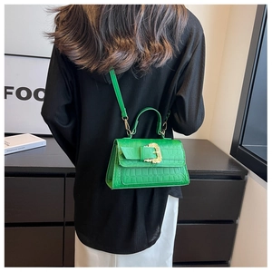 Detail of green crocodile texture handbag with gold buckle styled in a modern setting