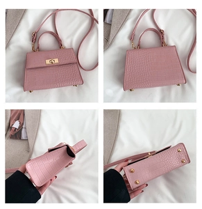 Detail view of pink crocodile pattern handbag with golden buckle and adjustable strap