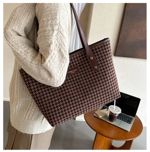 Detailed view of the large houndstooth tote bag worn by model in a modern office setting