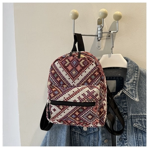 Detail of ethnic geometric woven backpack with vibrant diamond patterns and black zip pocket