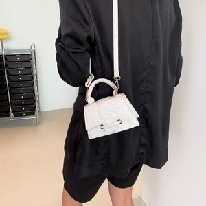 White embossed leather mini tote bag with crossbody strap shown on black blazer outfit