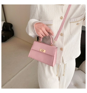 Detail of pink croc-embossed mini square bag with golden rotary clasp and shoulder strap