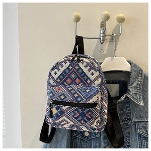Ethnic style mini backpack with colorful geometric patterns hanging on a metal wall hook