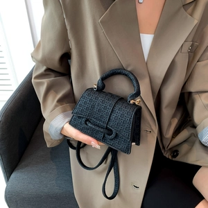 Chic black woven handbag with gold hardware and shoulder strap shown in a lifestyle setting