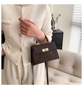 Detail of dark brown crocodile pattern handbag with golden rectangle twist lock