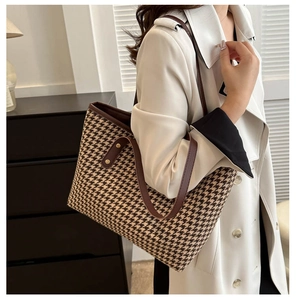 Detail of brown houndstooth tote bag with leather straps and gold rivets for autumn