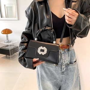 Sac à bandoulière noir chic avec boucle strass et poignée plissée porté par un modèle