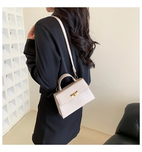Detail of the crocodile pattern texture and golden metal twist lock on the cream handbag