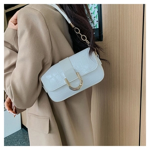 Detail of white crocodile-embossed handbag with gold horseshoe buckle and chain strap