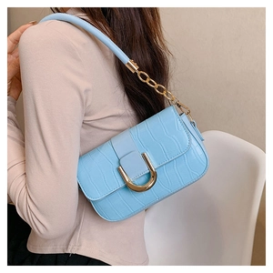Detail of light blue faux crocodile leather shoulder bag with golden U-shaped buckle strap