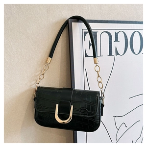 Detail of black crocodile-embossed leather bag with gold horseshoe buckle and chain