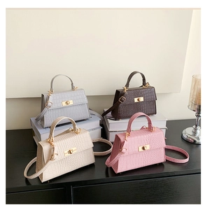 Close-up of four crocodile pattern crossbody bags in blue, brown, beige, and pink