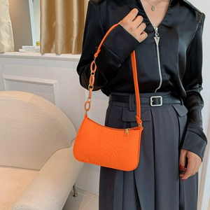 Orange croc-effect shoulder bag with resin chain strap shown on a female model