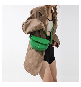 Modella che indossa una borsa a sella in pelle opaca verde con logo Fashion & Bags