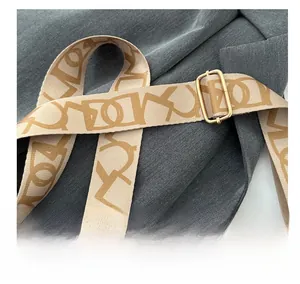 Détail de la bandoulière tissée beige avec motifs géométriques et boucle dorée chic