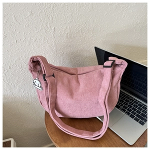 Detailed texture of pink corduroy crescent bag with a cute white dog charm on table