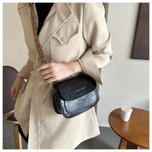 Gros plan sur le sac besace noir avec bandoulière vintage et détails logo