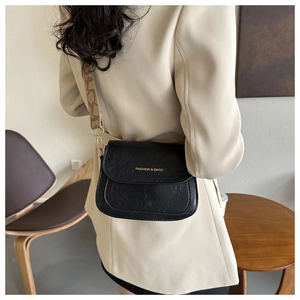 Détail du sac selle noir avec texture PU vintage et bandoulière en jacquard