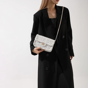 White tweed crossbody bag with gold chain strap and metallic lock shown on model