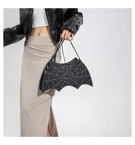 Detail of bat-shaped black PU leather handbag with white spiderweb patterns and heart detail