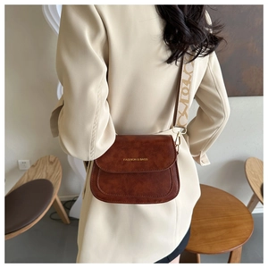 Détail du sac besace en cuir marron avec logo tendance et bandoulière à motifs sur modèle