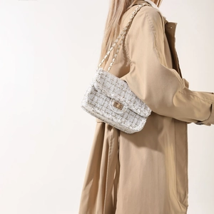 Elegant beige tweed crossbody bag with gold chain strap worn by model in trench coat