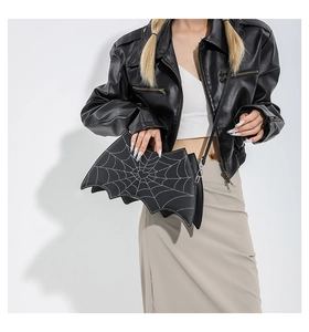Detail of bat-shaped crossbody bag with white spider web pattern on black matte faux leather