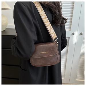 Détail d'une besace marron foncé en cuir avec large bandoulière en jacquard