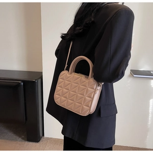 Quilted crossbody bag in beige leather worn over a black blazer for a minimalist look