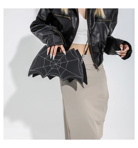 Detail of bat-shaped crossbody bag featuring white spider web stitching and silver hardware