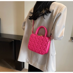 Detail of rose pink quilted handbag featuring golden hardware and leather texture