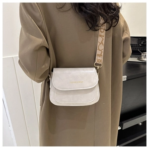 Détail du sac bandoulière blanc cassé avec ferrures dorées et sangle en jacquard
