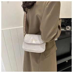 Détail du sac bandoulière beige clair avec une large bandoulière imprimée tendance